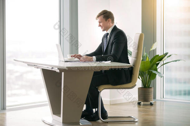 在<strong>现代办公桌</strong>上使用笔记本电脑的商人