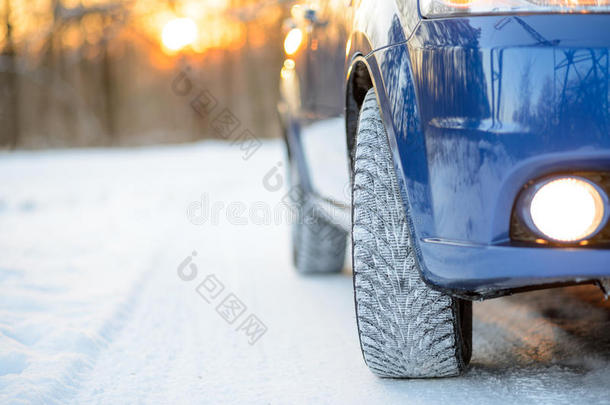 雪路上有冬天轮胎的蓝色汽车。 开车安全。