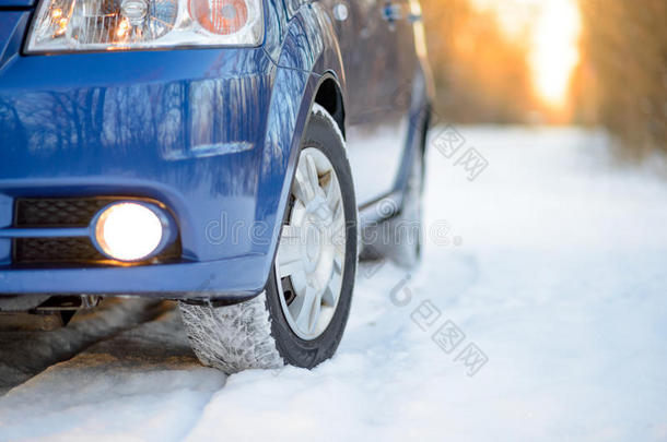 雪路上有冬天轮胎的蓝色汽车。 开车安全。