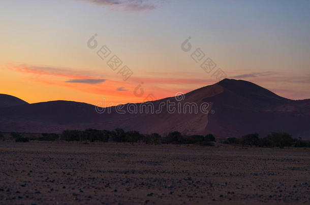 五颜六色的日落在纳米比亚沙漠，纳米比亚，非洲。 风景秀丽的沙丘背光在纳米布诺克洛夫特国家公园，斯瓦克普