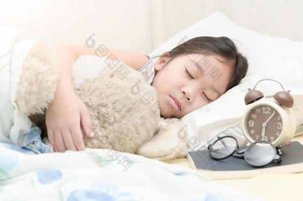 可爱的小亚洲女孩睡觉，拥抱泰迪熊在床上