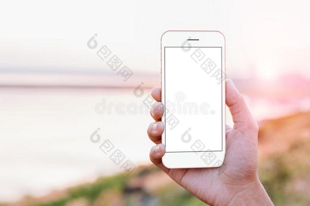 特写手持手机手机显示屏幕在户外日落时间，模拟新的现代智能手机