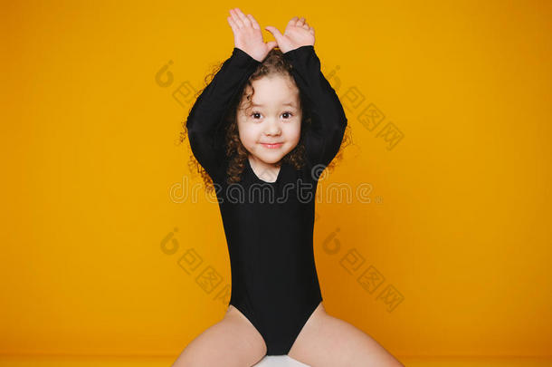 有趣的小女孩用手在橙色的背景上<strong>做兔子</strong>的耳朵。 复制空间