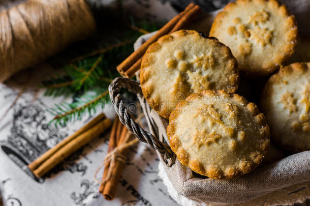 圣诞馅饼在柳条篮子里，放在老式亚麻布上，上面有肉桂棒和冷杉树枝