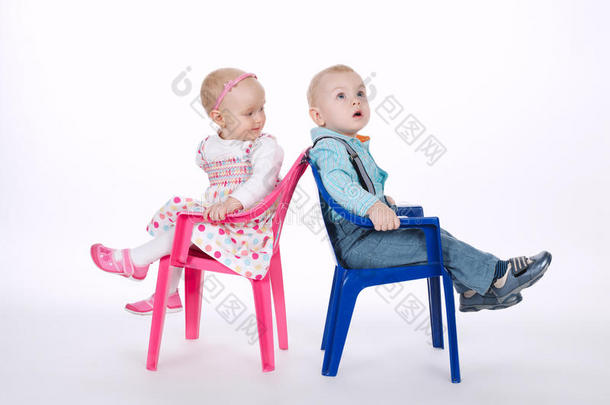 有趣的男孩和女孩背靠背坐在椅子上
