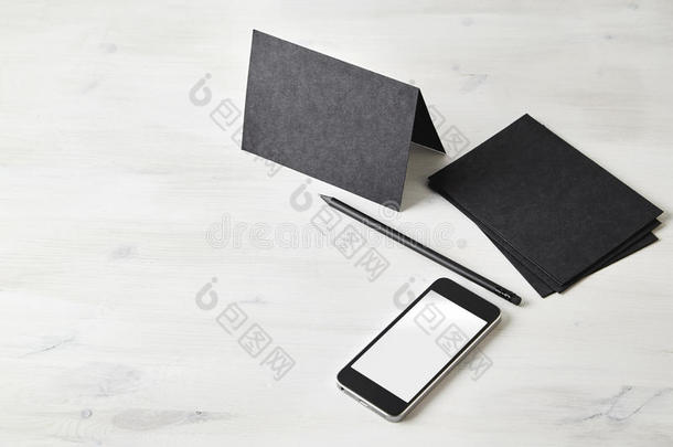 空白文具布局。 黑色明信片，铅笔，木制桌子上的手机