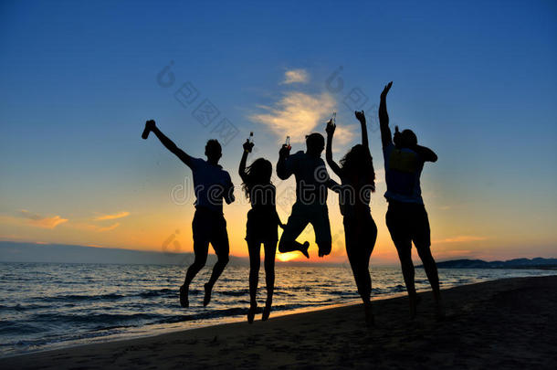 一群快乐的年轻人在美丽的夏日日落海滩上跳舞