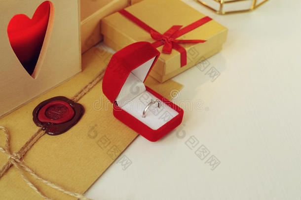 在红色天鹅绒盒子里订婚钻石戒指。 信封上有蜡封，周围有礼物