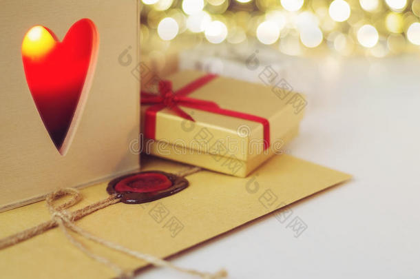 信封上有蜡封，周围有礼物和蜡烛，木箱里有心形的洞