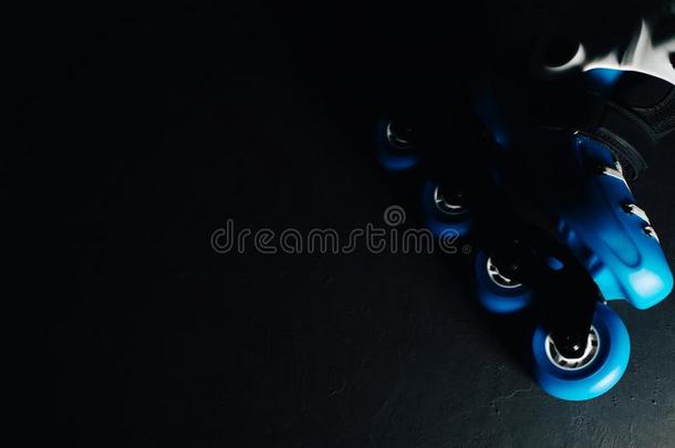 近景的蓝色溜冰鞋，内联溜冰鞋或轮滑在深色背面