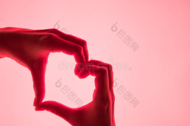 手以心红色背景的形式。 用手象征心脏。 情人节卡片。 女人`手的轮廓以心脏的形式出现。