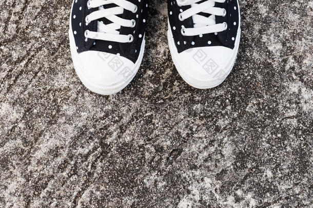黑白圆点女人运动鞋在混凝土地板上