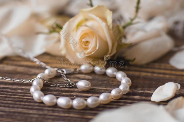 美丽的珍珠手镯和项链在优雅的花背景上，特写。 场的浅深度