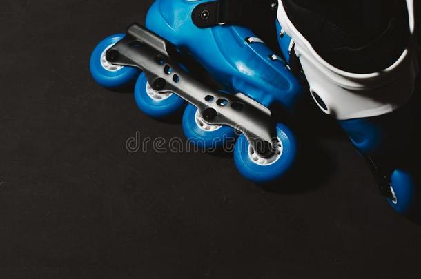 近景的蓝色溜冰鞋，内联溜冰鞋或溜冰鞋在深色背面
