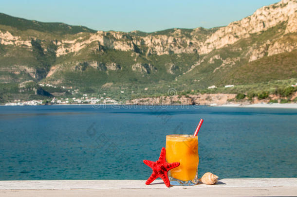 海边背景上的新鲜橙汁。