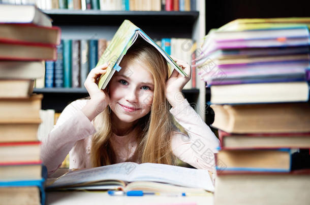 可爱的小女孩躲在书<strong>底下</strong>，靠近一堆书