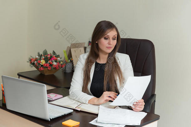 美丽微笑的商务妇女在她的办公桌上工作，带着文件。
