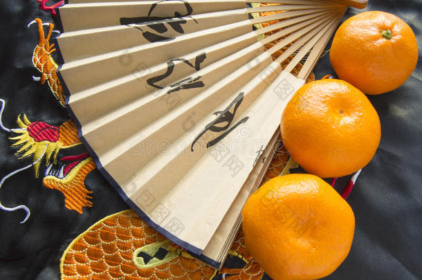 农历新年，橘子和扇子躺在丝织物上绣着龙