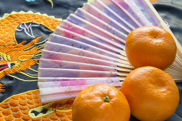 农历新年，橘子和扇子躺在丝织物上绣着龙