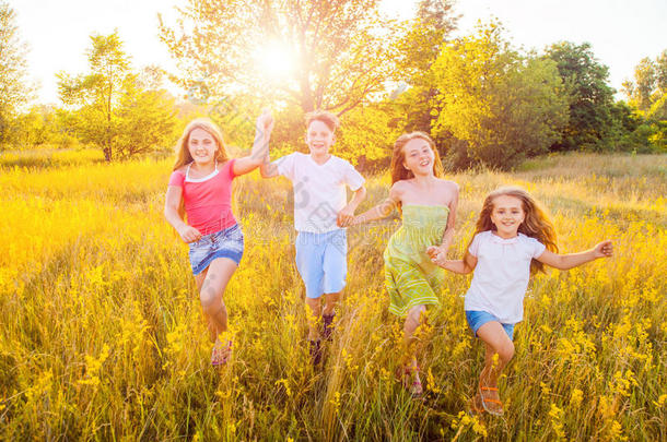 四个快乐的美丽的孩子在美丽的夏天一起奔跑，一起玩耍。