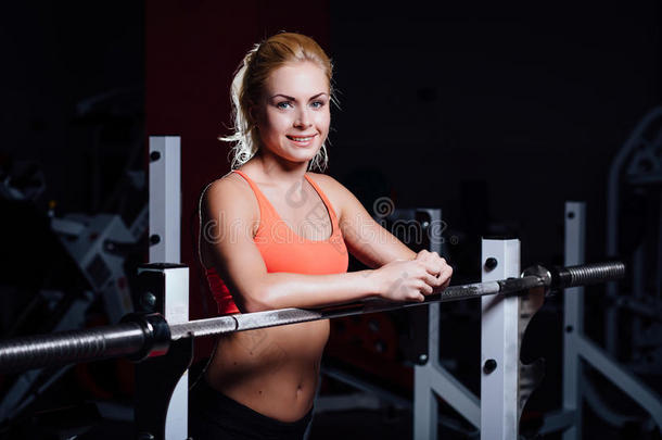 金发健身女孩，完美的形状身体休息后，运动锻炼在健身房依靠杠铃