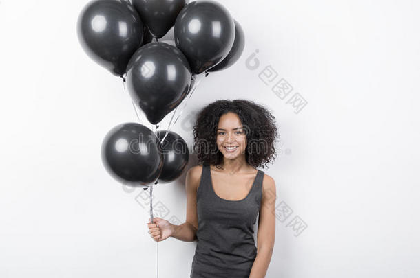 黑发女人微笑着拿着一束黑气球