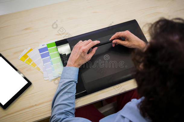 平面设计师和一个平面平板电脑坐在他的桌子上