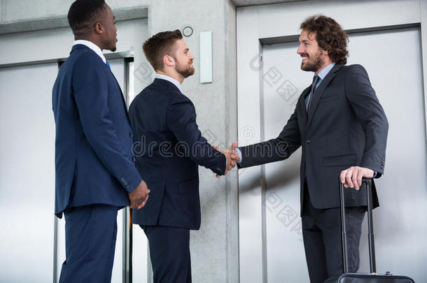 商人在等待电梯时握手