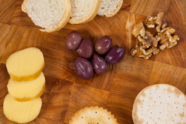 木板上的奶酪、面包、橄榄、饼干和核桃