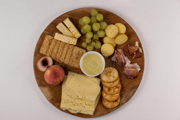 不同类型的奶酪，脆饼干，水果和酱汁在木板上