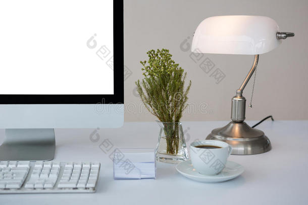 台式电脑，桌上有咖啡和台灯