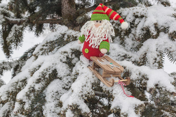 侏儒玩具与雪橇在白雪覆盖的树枝上产生了p