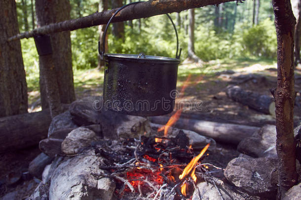 大锅在森林里的火上沸腾。 在行进中，一个平底锅准备食物。 冒险旅游，野营，在火上做饭