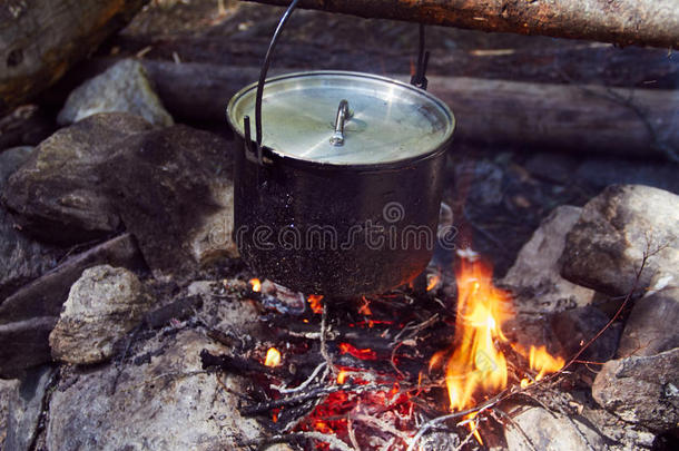 大锅在森林里的火上沸腾。 在行进中，一个平底锅准备食物。 冒险旅游，野营，在火上做饭