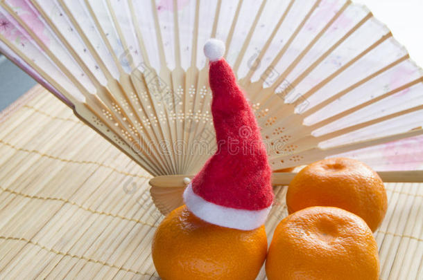 中国新年橘子帽子和手扇在竹席上