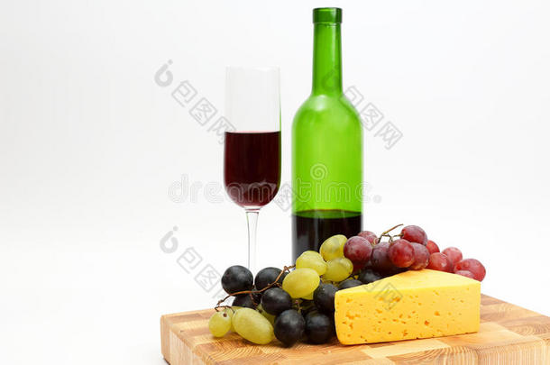 一杯红酒和一瓶白色背景上的葡萄