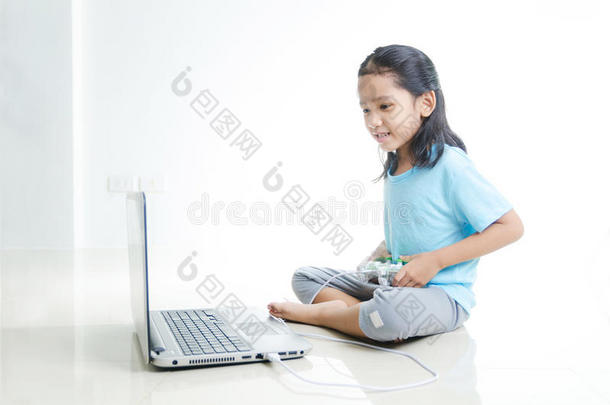 亚洲小女孩玩笔记本电脑和操纵杆控制器的游戏