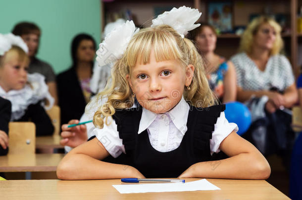 一年级的女孩坐在第一节课的桌子旁。 知识日