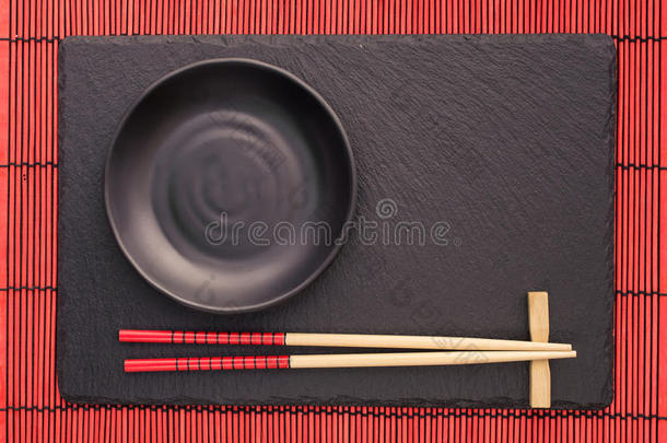 筷子和黑色盘子在石板过山车上的红色竹卷