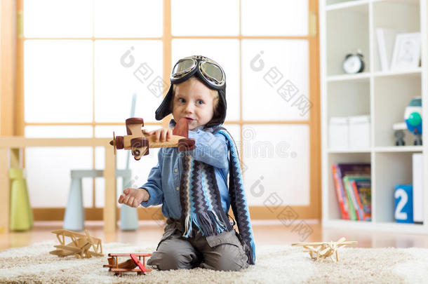 孩子穿得像飞行员一样在家里玩玩具飞机
