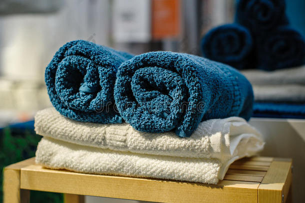 四条干净的软双浴巾，一套不同颜色的堆叠，躺在木椅上