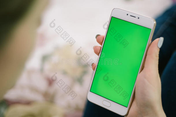 漂亮的女孩手里拿着智能手机，手里拿着绿色屏幕，手里拿着手机