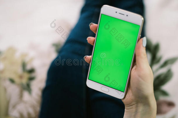 漂亮的女孩手里拿着智能手机，手里拿着绿色屏幕，手里拿着手机