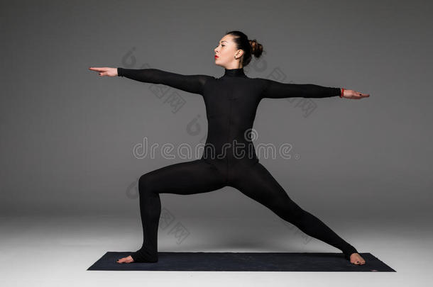 美丽的瑜伽女人在灰色背景上练习瑜伽姿势。