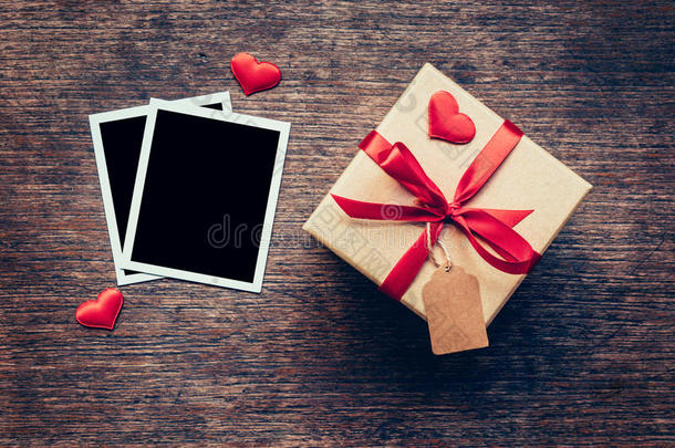 空白相框和礼品盒，红色的心在木材背景上