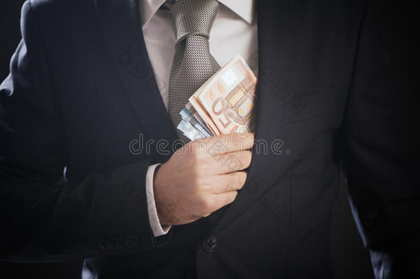 一个商人把钱藏在西装夹克口袋里。