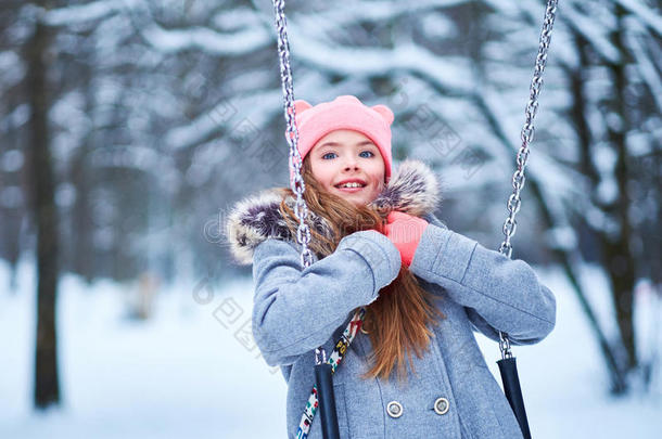 迷人的小女孩在下雪的冬天秋千上