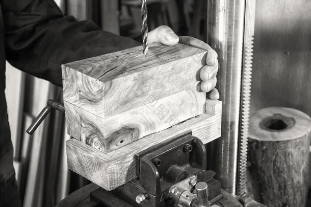 木匠工作场所-男人使用钻压在木材上。