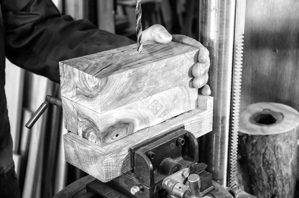 木匠工作场所-男人使用钻压在木材上。