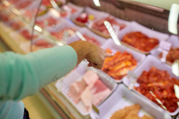 顾客用手指着杂货店摊位上的肉
